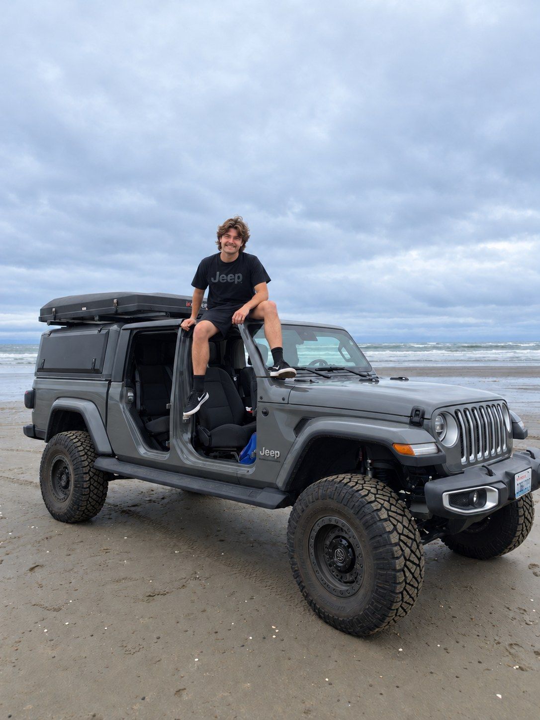 Nic sitting on top of his Jeep on the beach